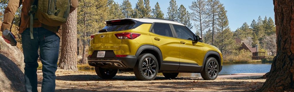 An All-New Nitro Yellow Metallic Chevy Trailblazer parked on the dirt within the trees, right next to a dock and body of water in Oxford, NC.