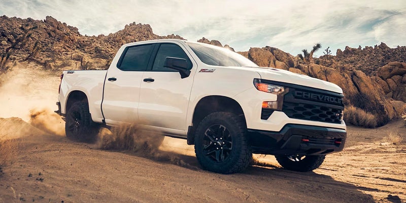 An all-new white 2024 Chevrolet Silverado 1500 driving through sand dunes. - Boyd Chevrolet GMC Oxford, NC
