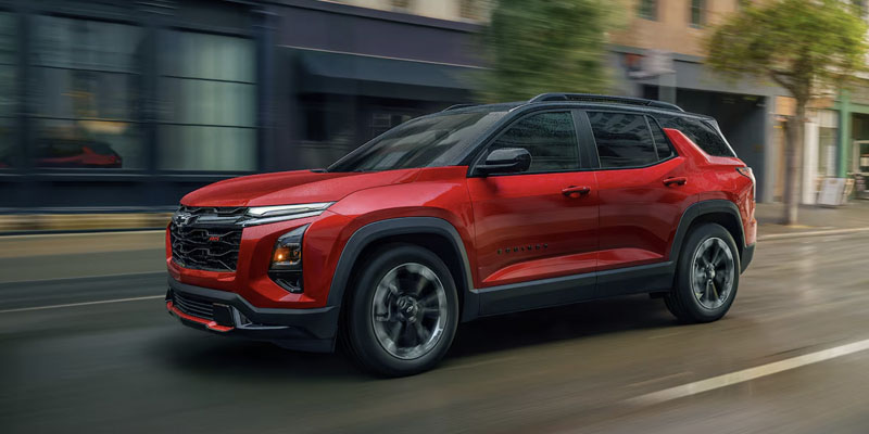 An all-new red 2025 Chevy Equinox driving through a downtown street. - Boyd GM Oxford, NC