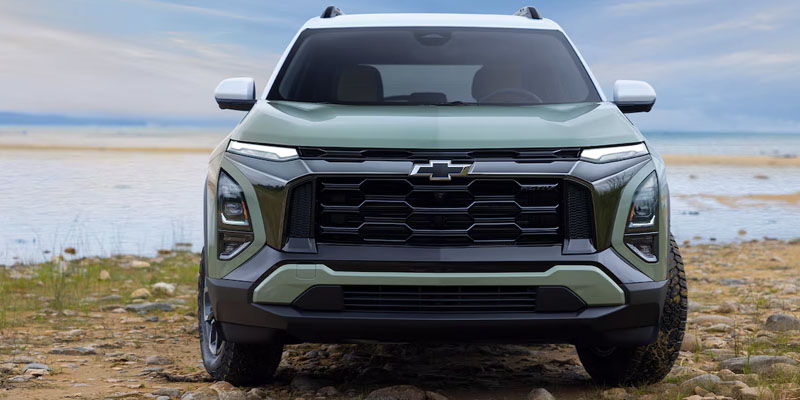 An all-new cacti-green 2025 Chevy Equinox parked in front of a body of water on the beach. - Boyd GM Oxford, NC