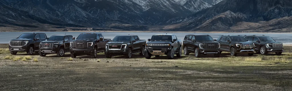 GMC vehicle lineup in a rugged outdoor setting.