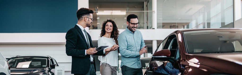 Car dealership finance consultation with customers reviewing vehicle options