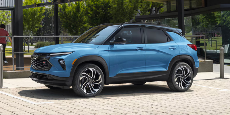 Blue Chevrolet Trailblazer parked outside a modern glass building.