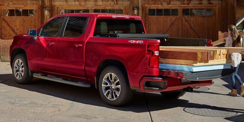 Silverado 1500 with the tailgate down, loaded with heavy wooden lumber.